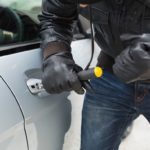 Thief breaking into car with screwdriver in broad daylight